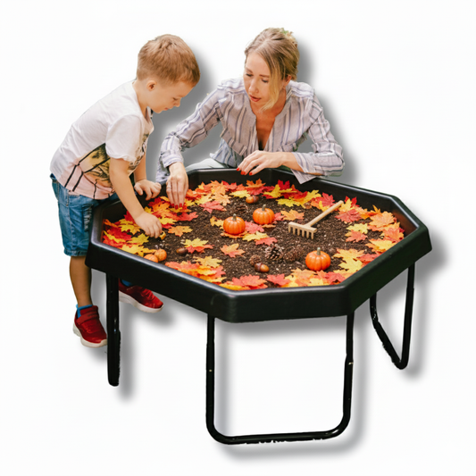 Large TUFF PLAYtray with adjustable stand used for sensory play with soil, autumn leaves, pine cones, and small pumpkins by a child and adult