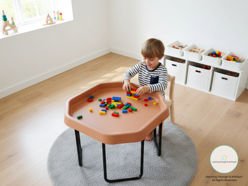 Child playing with colorful blocks on a octagon play table in a bright room.